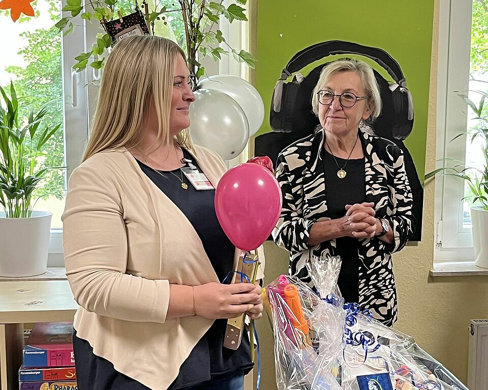 Mitarbeiterin mit Ballon, im Hintergrund die Bürgermeisterin
