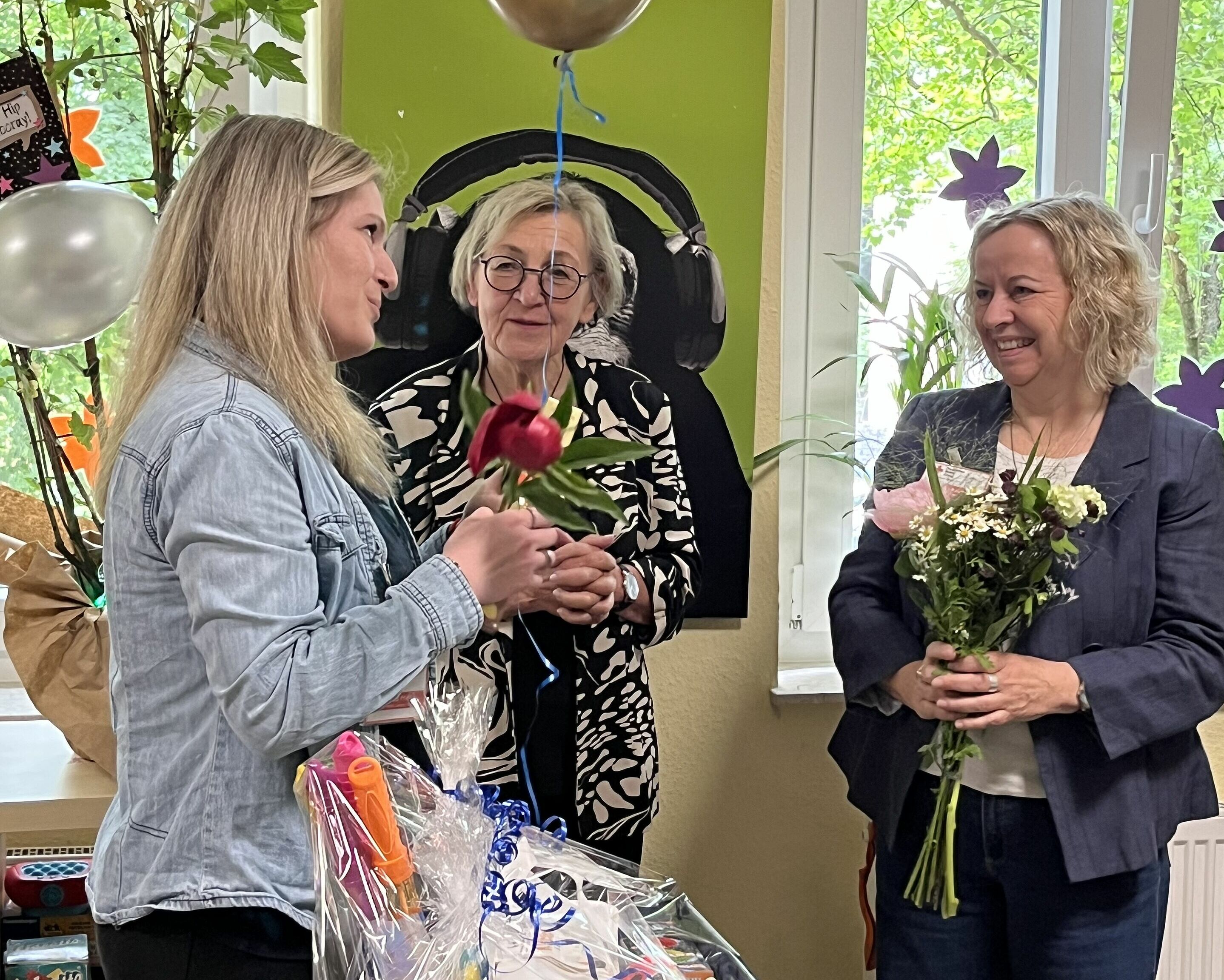 Mitarbeiterin bekommt Blumen überreicht