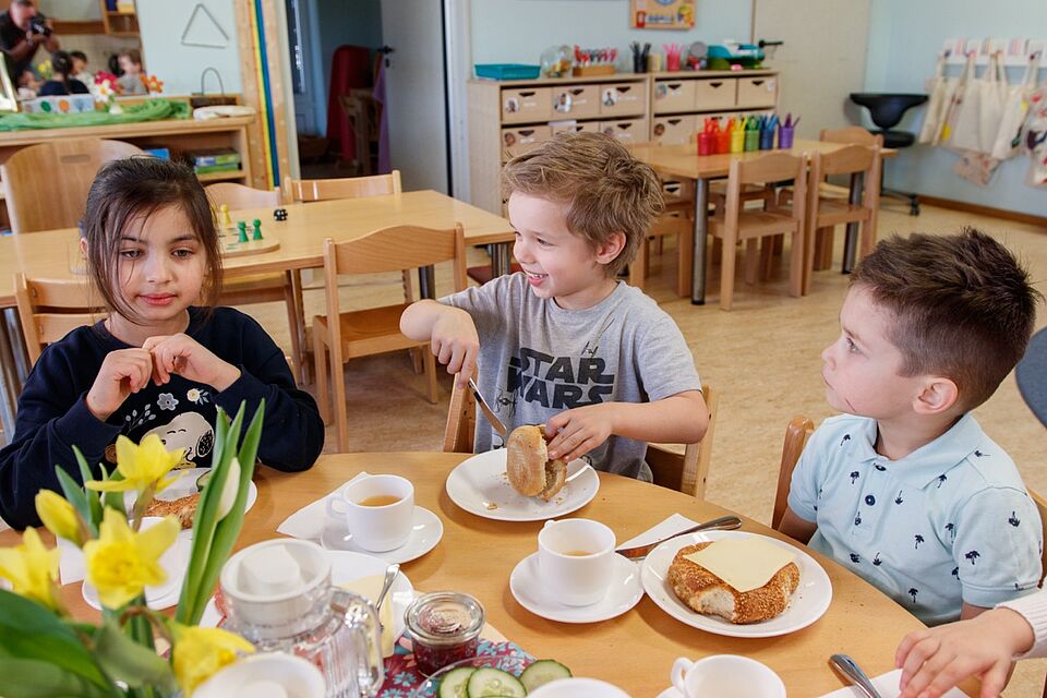 Kinder sitzen gemeinsam am Tisch und frühstücken