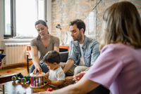 Drei Erwachsene und ein Kind am Tisch mit Spielzeug